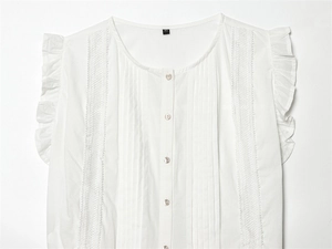 Detailed macro view of white sleeveless shirt with lace trim and mother of pearl buttons