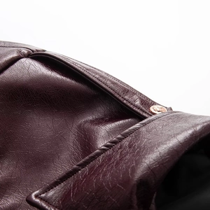 Detailed close-up of dark wine red patent leather jacket with embossed gold metal button