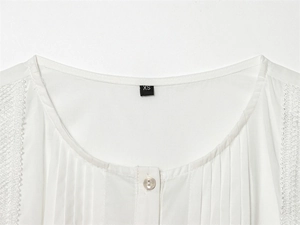 Detail of white cotton blouse showing pintuck pleats, lace trim, and shell button