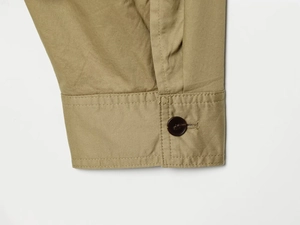 Détail macro du poignet de la veste en sergé kaki avec bouton marron et coutures