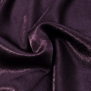 Détail du tissu plissé violet foncé avec un éclat de soie métallique et texture lisse