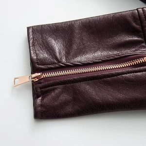 Detail of premium wine red patent leather jacket with rose gold zipper and precise stitching