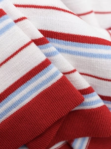 Macro detail of knit fabric featuring classic red and blue stripes with ribbed hem finish