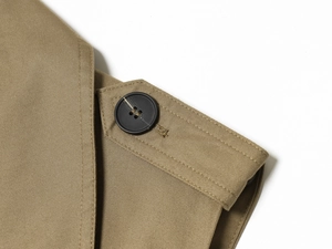 Détail macro de l'épaulette en sergé kaki et bouton en résine mate sur le gilet