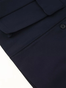 Macro detail of navy blue blazer fabric featuring flap pocket and classic four-hole button