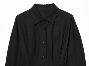 Détail de chemise noire à manches longues avec col et plis structurés à la taille