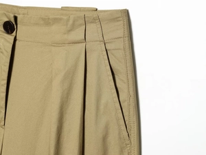 Détail du pantalon plissé en sergé kaki montrant le bouton et la poche latérale