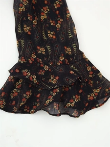 Detailed macro view of black chiffon dress sleeve with red floral pattern and ruffles