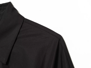 Détail du col et de l'épaule d'une chemise noire avec coutures précises et texture textile