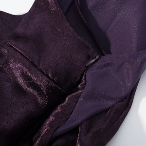 Détail d'une robe en maille métallique violet foncé avec fermeture éclair et plis fins