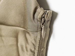 Detailed close-up of a concealed zipper closure on a satin halter dress fabric