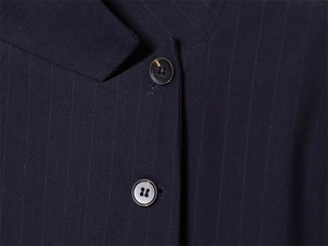 Macro shot of navy pinstripe suit fabric with polished buttons and precise tailoring