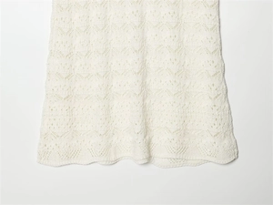 Close-up detail of white knitted dress showing intricate hollow wave pattern texture