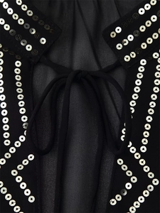 Close-up detail of black blouse with silver sequins and tie-up neckline craftsmanship