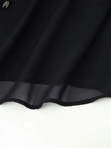 Macro detail of black chiffon fabric showing elegant waves and silver bead accents