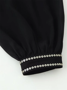 Detail of black shirt cuff with double row of silver sequins and pleated wrist design