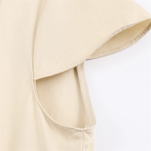 Detailed close-up of layered petal sleeve stitching on a beige woven summer dress