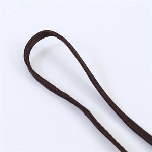 Detail shot of the adjustable spaghetti strap on a brown satin dress with fine stitching