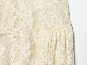 Détail du tissu en dentelle florale avec passepoil en velours et ourlet plissé