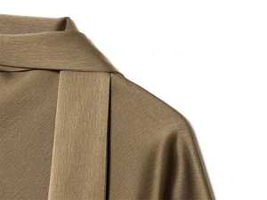Detailed close-up of dark olive satin shirt texture and premium stitching on the collar