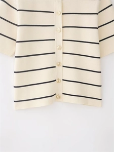 Dettaglio del cardigan in maglia a righe crema con bottoni in metallo dorato