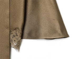 Detail of silk satin fabric with elegant eyelash lace trim in olive green finish