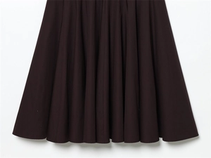 Detailed close-up of dark brown pleated skirt with vertical folds and flared hemline