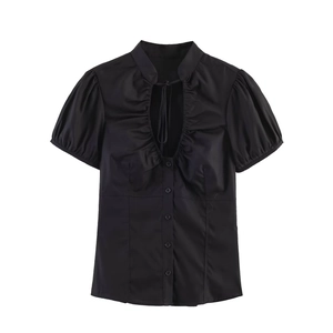 Detail of black poplin top with pleated stand collar, V-neck cutout and bow tie closure