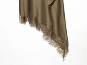 Detail of satin dress hem with delicate eyelash lace trim and irregular slanted cut
