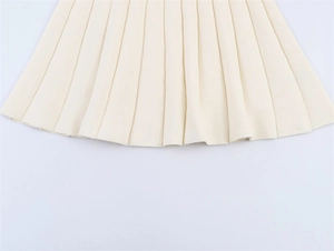 Detailed macro view of beige pleated knit dress hemline with sharp vertical pleats
