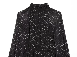 Detailed view of high neck pleats and white polka dots on lightweight black chiffon dress