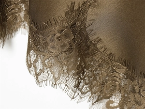 Close-up of olive satin fabric featuring delicate eyelash lace trim for elegant dresses