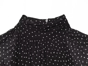 Close-up of ruffled high collar on polka dot chiffon dress with a silver back zipper