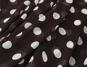 Dettaglio ravvicinato di tessuto chiffon marrone a pois bianchi e trama plissettata