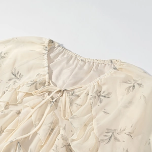 Dettaglio camicetta in chiffon a fiori con scollo a balze e chiusura con fiocco