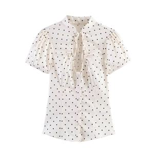 Close-up of vintage white polka dot blouse featuring a bow neck and pleated detail