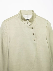 Detail of pale green linen jacket with stand collar and retro embossed metal buttons
