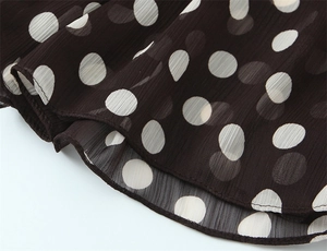 Dettaglio macro di tessuto in chiffon nero a pois bianchi con texture a pieghe verticali