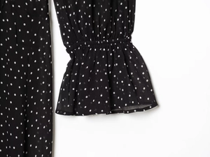 Detailed view of elastic ruffled cuffs on a black polka dot chiffon dress for women