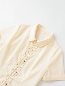 Détail de la blouse en popeline crème avec volants et clous métalliques argentés