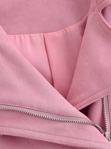Détail d'une veste en faux daim rose avec une fermeture éclair argentée et doublure