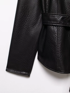 Close-up of black faux leather jacket showing pebbled texture, belt loops and neat stitching