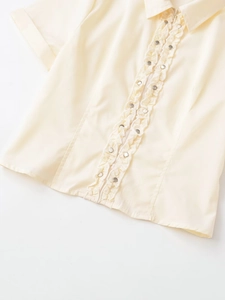 Détail de chemise en popeline beige avec volants et finitions à rivets métalliques