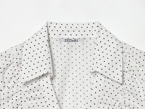 Detailaufnahme von weißem Popeline-Hemdkragen mit schwarzem Punktmuster und Markenetikett