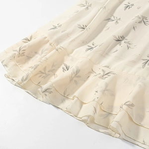 Dettaglio dell'orlo a balze sovrapposte su abito in chiffon bianco avorio con fiori