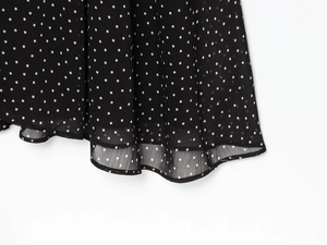 Detailed view of lightweight black chiffon fabric with white polka dots and layered hemline