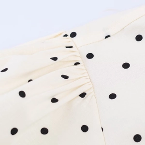 Macro view of cream poplin top showing black polka dots and pleated puff sleeve detail