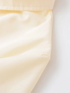 Vue détaillée de la texture popeline crème et des coutures précises sur la chemise à rivets