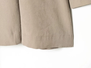 Detailed macro view of the khaki trench coat hem with professional stitching and fabric texture