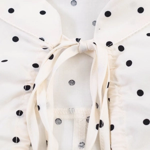 Macro detail of polka dot poplin top neckline with decorative bow tie-knot and soft pleats